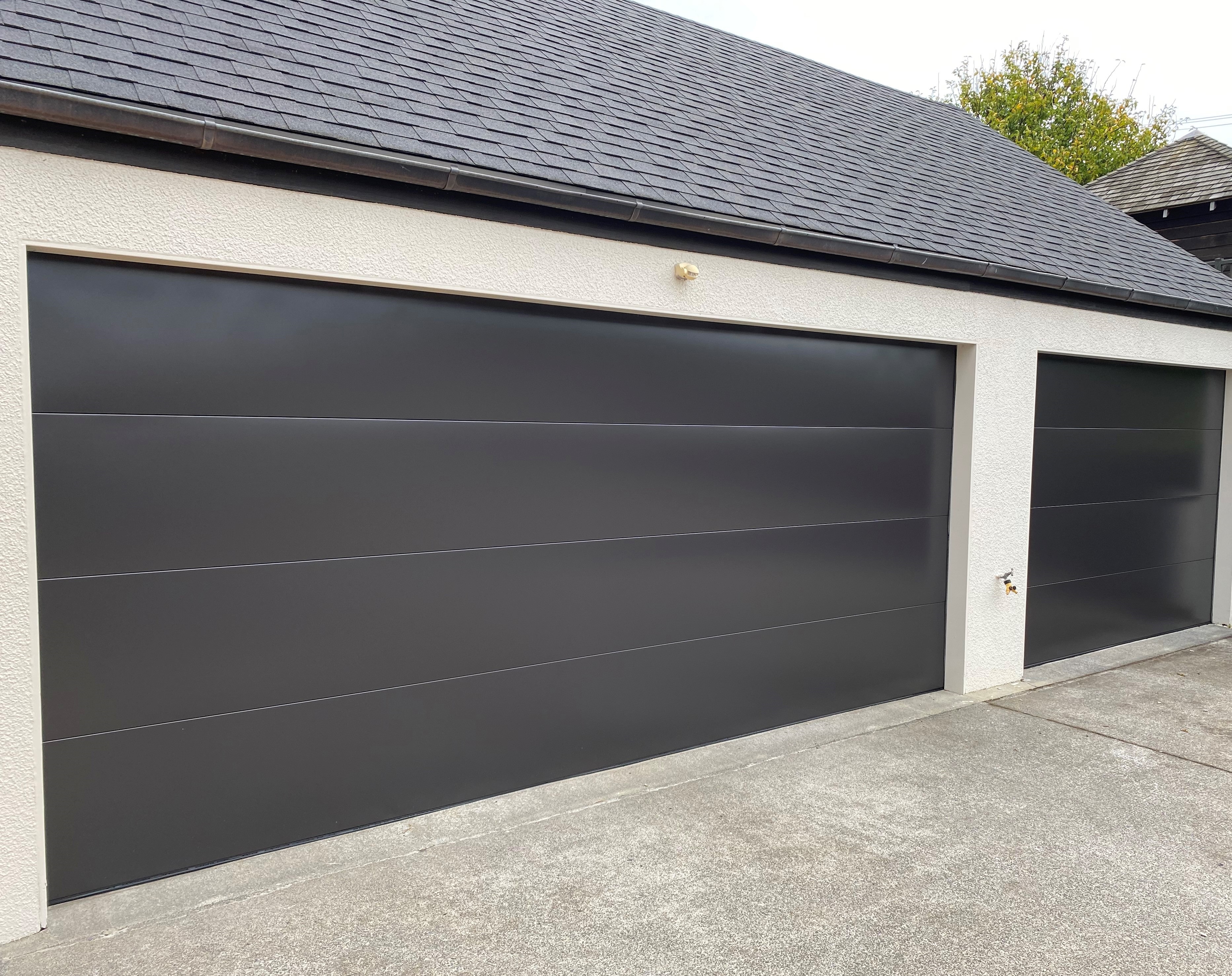 Modern dark sectional garage door installed on Auckland residential property